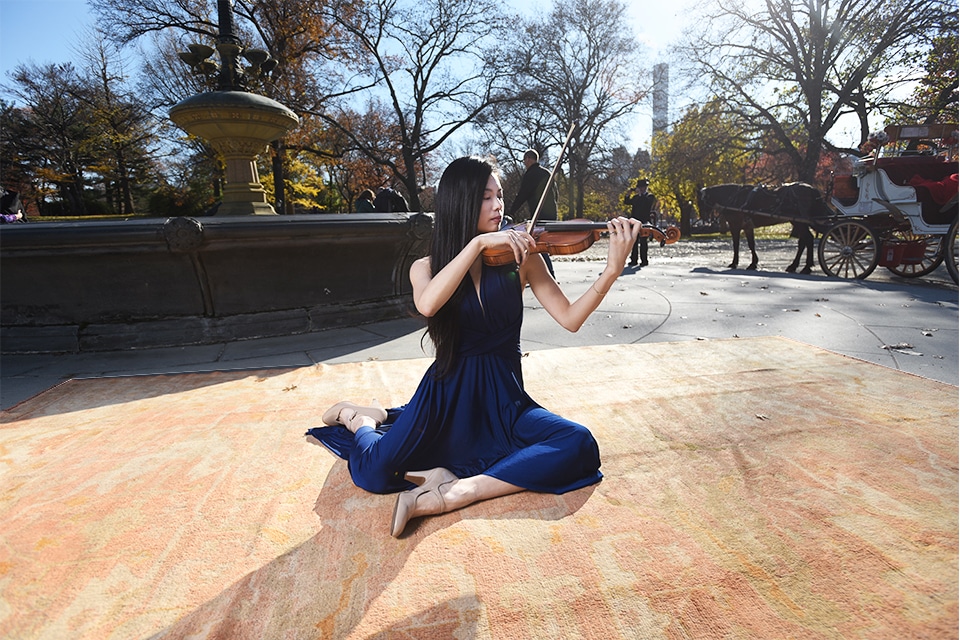 Antique Turkish Oushak Rug by Nazmiyal Antique Rugs at Central Park Violinist plays on an antique rug by a fountain in Central Park NYC